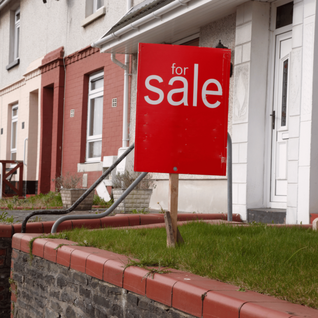 For Sale board in front of a row of terraced houses